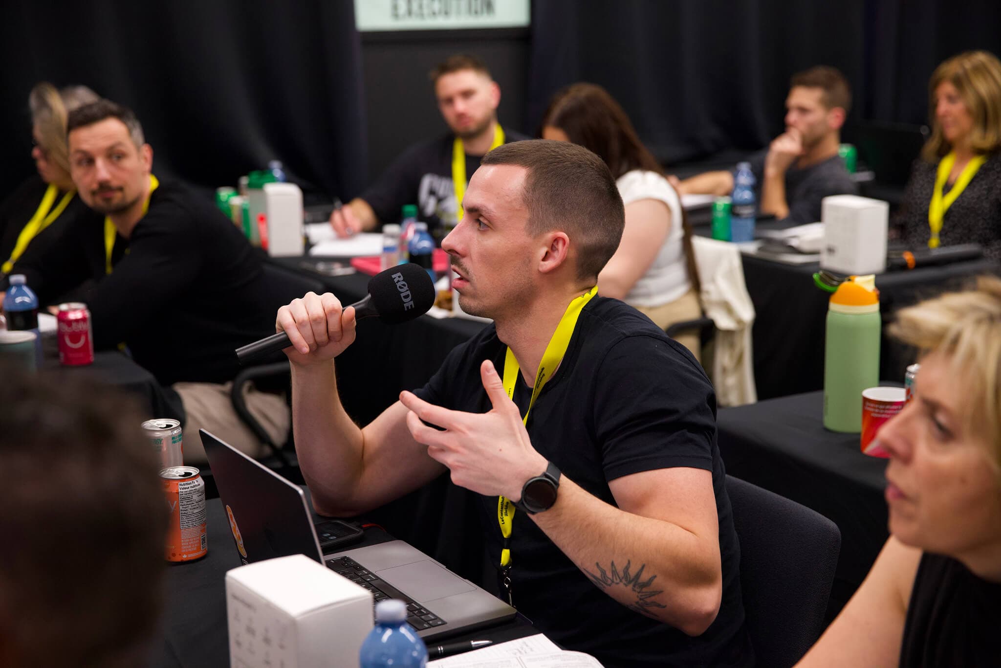 Un participant pose une question au micro, lanière jaune au cou