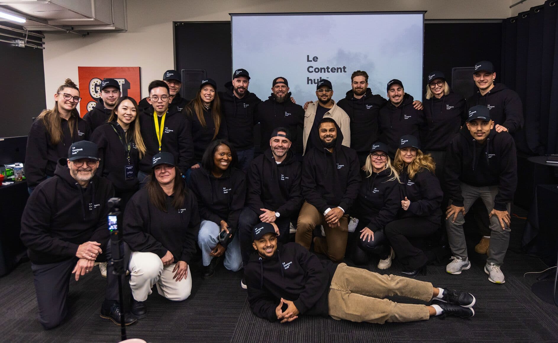 Photo de groupe en hoodies devant l'écran Le Content hub